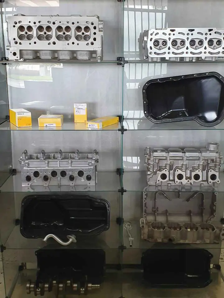 Vitrine de vidro da loja com quatro cabeçotes de alumínio, cárteres, um virabrequim e caixas de peças MAHLE
